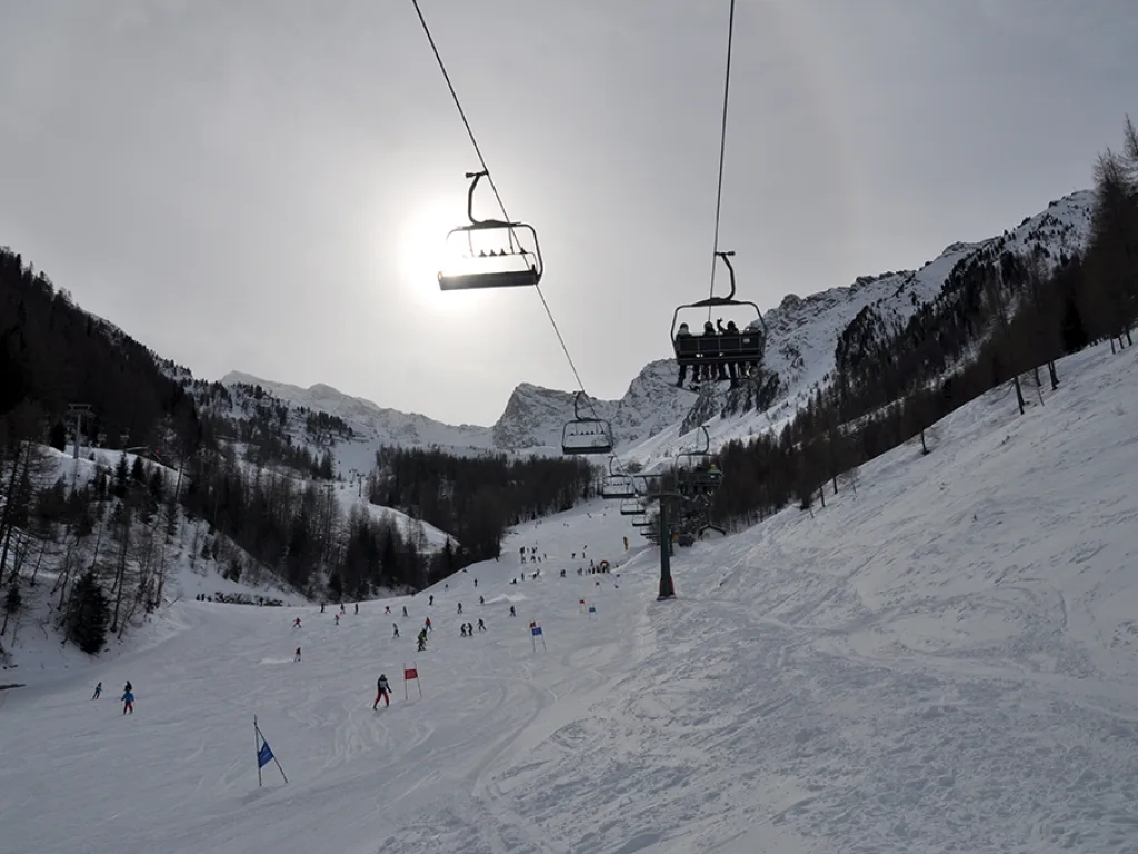 Sessellift und Piste im Gegenlicht der tief stehenden Sonne.